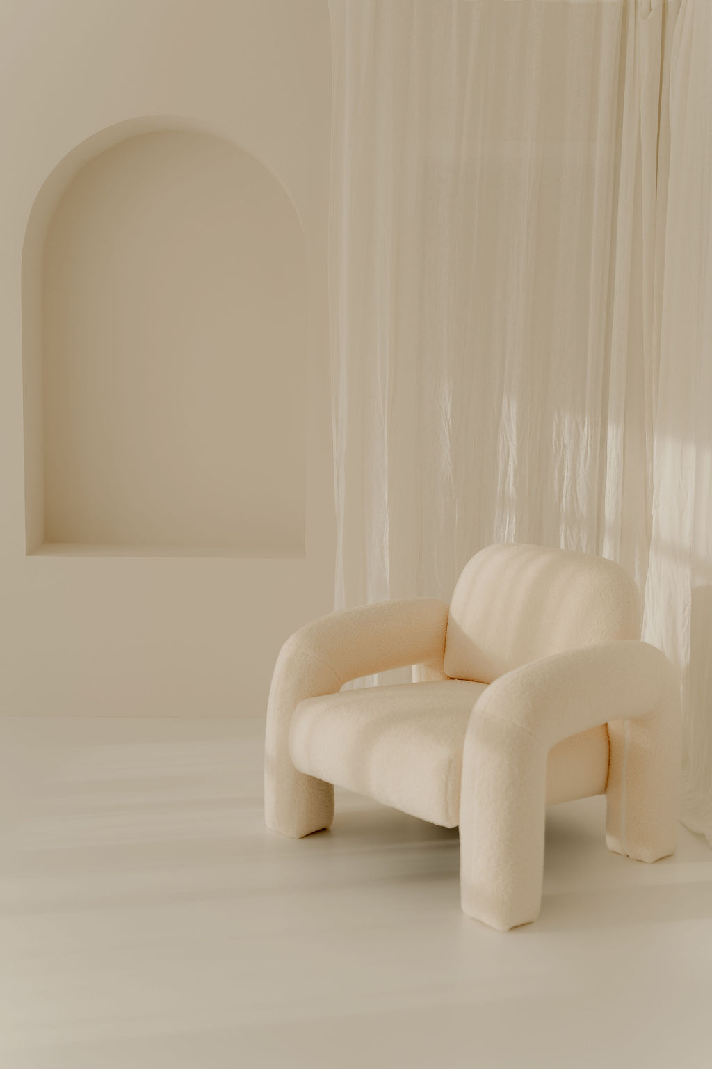 Landloft Studio - Plush cream armchair with flowing sheer curtains