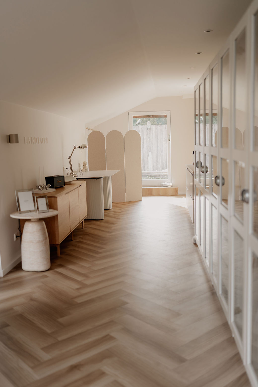 Landloft Studio - Weiter Studioüberblick mit Fischgrätboden und Glasschrankfront